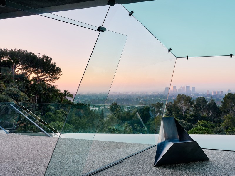 A l'aube, en regardant à travers l'enceinte en verre sans cadre inclinée du bureau de Goldstein, les angles dynamiques et les aménagements personnalisés minimaux créent une forme cristalline qui s'étend dans l'espace au-dessus de la terrasse et de la pisc